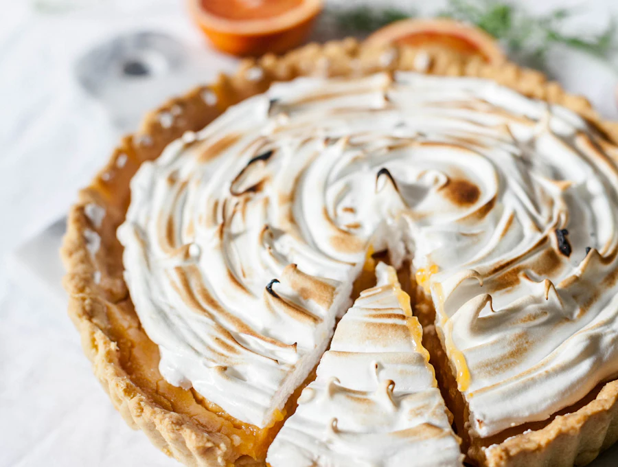 Lemon meringue tart beside a cup of coffee