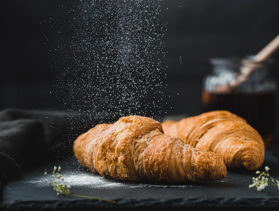 Butter croissants being dusted with icing sugar
